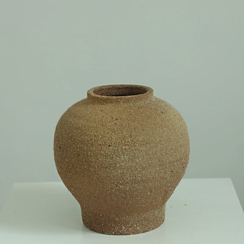 Brown Danish-style rough earthenware vase on white surface.
